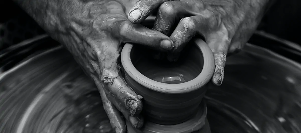 Hands creating a clay pot on a potter's wheel