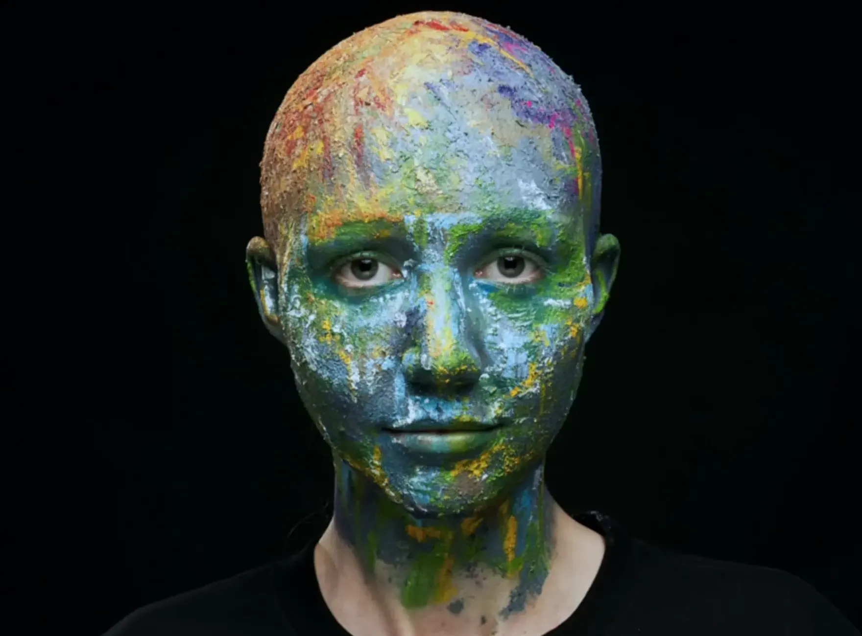 Woman's entire face painted with several colours including her bald head