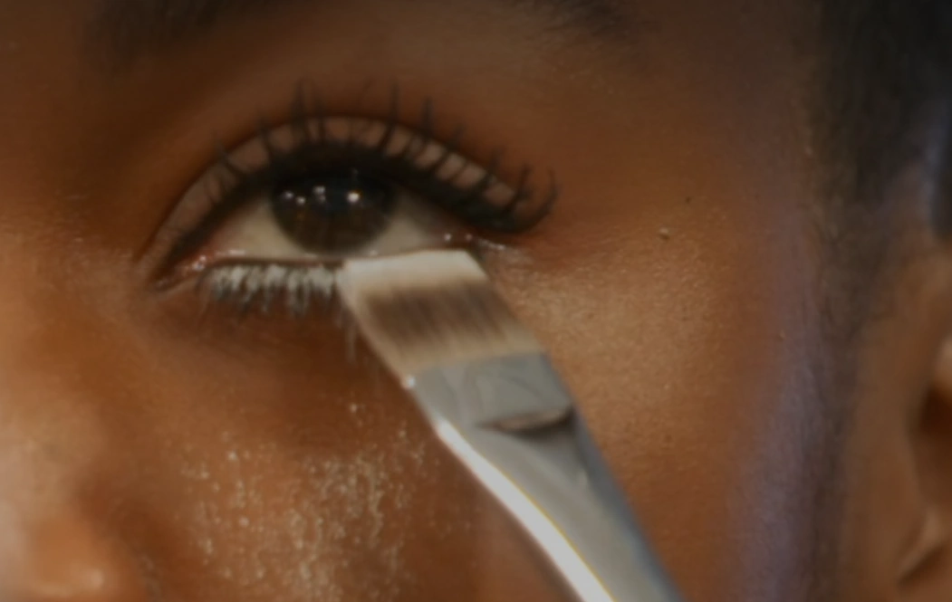 MUA applying powder to make the Clumpy Lash look