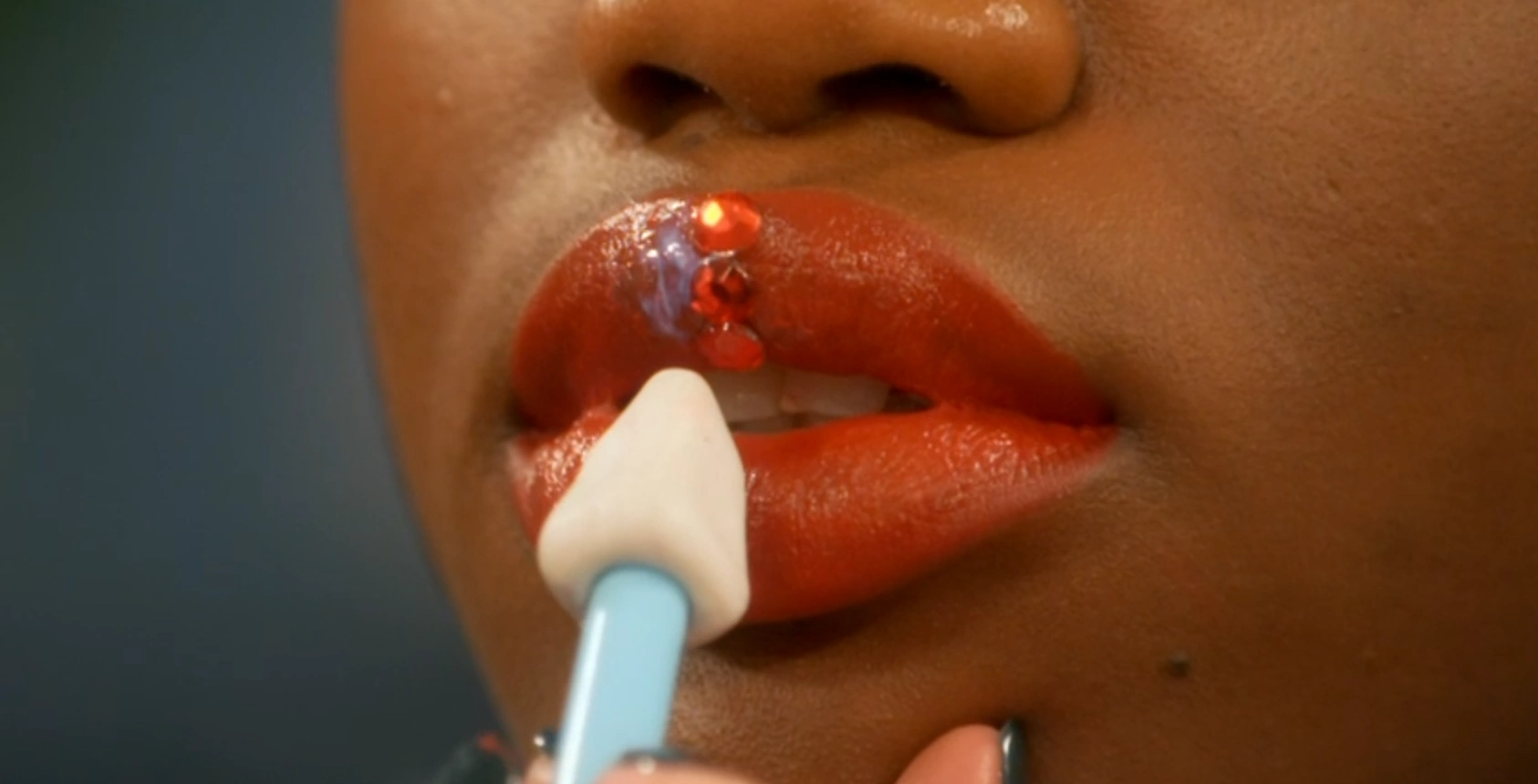 MUA applying jewels to a model's lip