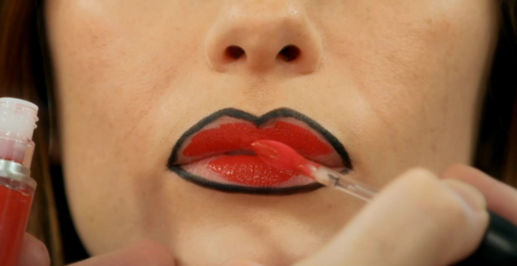 MUA filling in the lip with a liquid lipstick in a bright colour