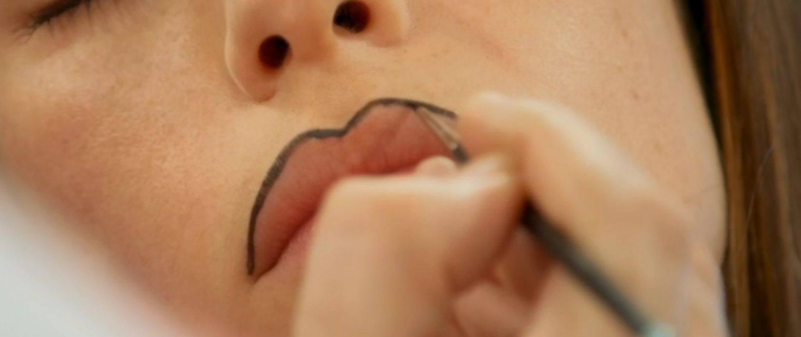 MUA applying outline of the lip