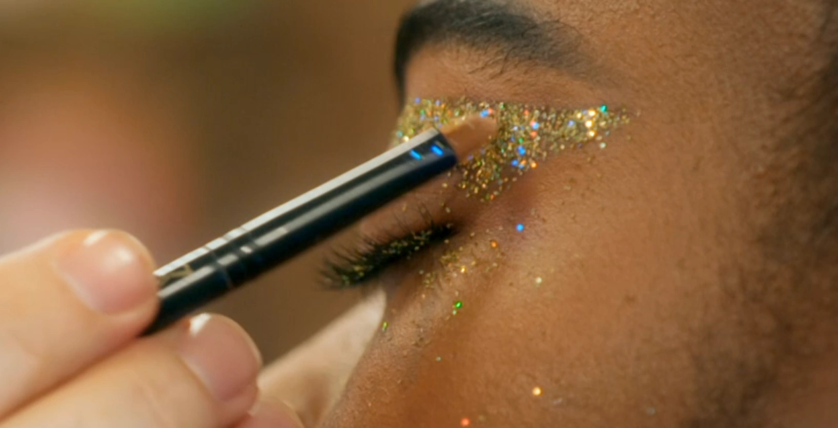 MUA applying glitter to the adhesive around the eye