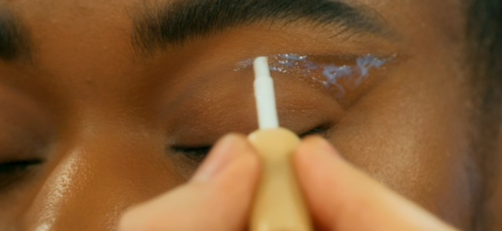 MUA applying lash glue around the eye of a model
