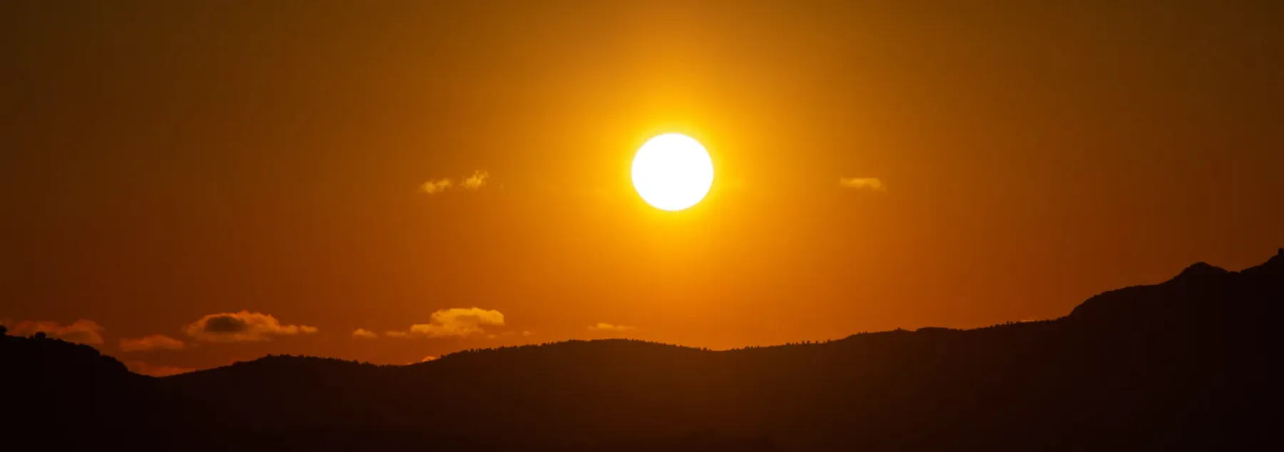 Sun appears low in the sky above a rural scene